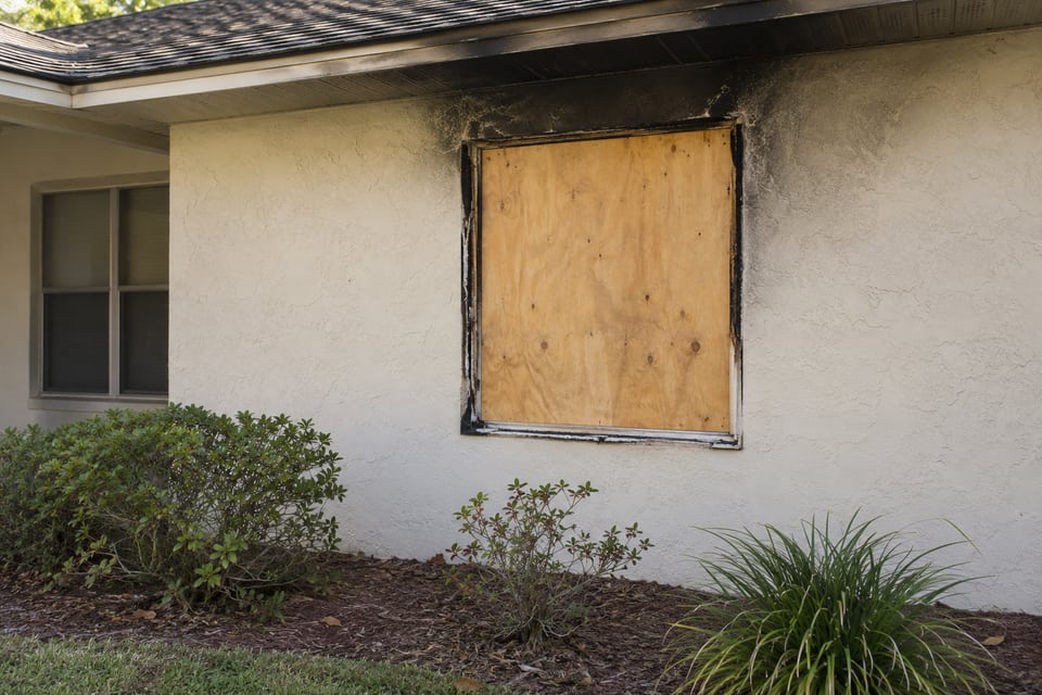 Illustrative fire-damaged window opening covered with plywood